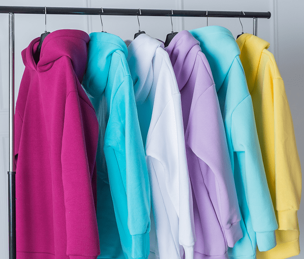 Colorful hoodies hanging on a clothing rack.