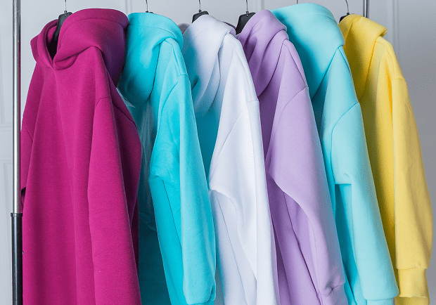 Colorful hoodies hanging on a clothing rack.